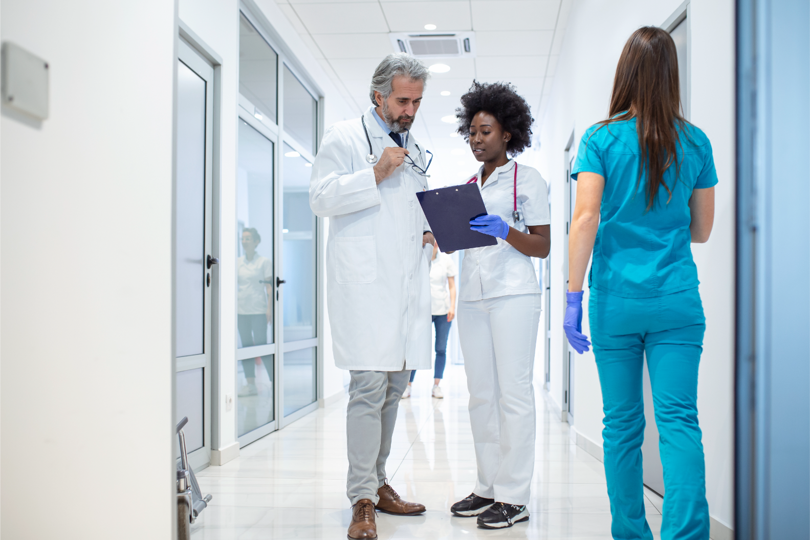 group-medics-with-clipboard-discussing-along-hospital-corridor-doctor-nurse-briefing-medical-report (1)